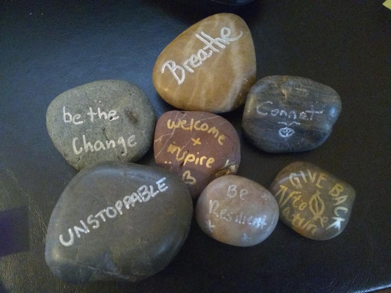 Polished rocks with sayings like "Breathe," "Unstoppable," and "be the change" on them